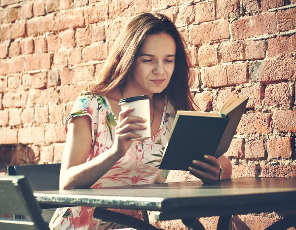 Hymyilevä tyttö istuu kesäterassilla kadulla kahvin kanssa — kuvapankkivalokuva