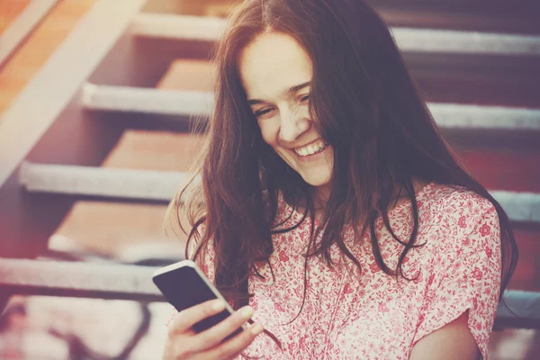 Sorrindo menina bonita segurando smartphone e usando aplicativo ou leitura — Fotografia de Stock