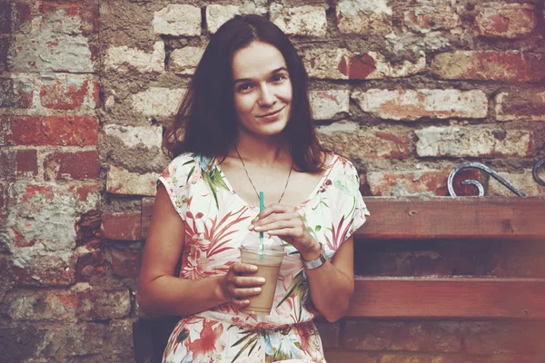 Bonita chica sonriente con batido de leche en el fondo de la pared de ladrillo — Foto de Stock