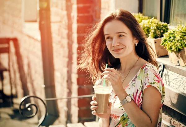 Söt leende flicka med mjölk shake sitter på bänken vid gatan c — Stockfoto