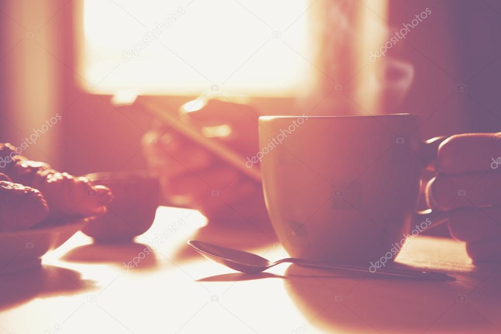 Fresh breakfast with hot coffee and browsing smartphone