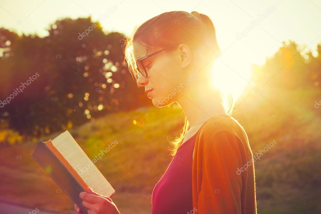 girl reading book in summer sunset light