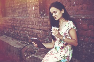 Dijital tablet pc ile kahve fincanı duvara yakın tutan kız