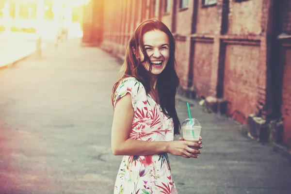 Hübsches lachendes Mädchen mit Milchshake, das morgens auf der Straße läuft — Stockfoto