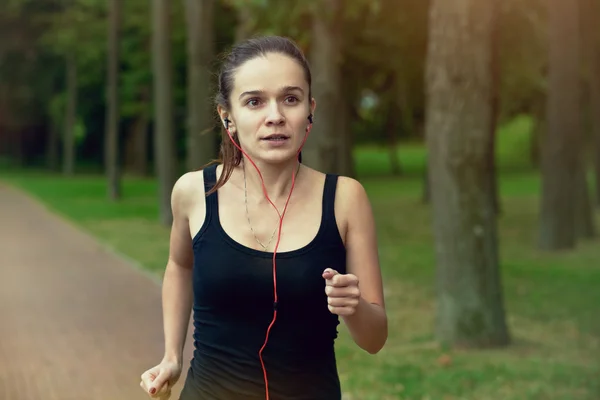 Docela sportovní žena jogging v parku — Stock fotografie