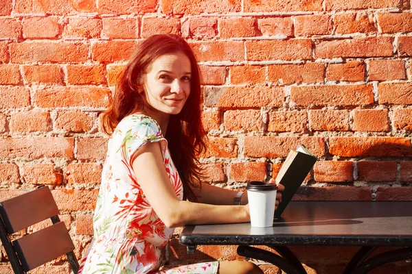 Chica sonriente sentada en la terraza de verano en la calle con co mañana — Foto de Stock