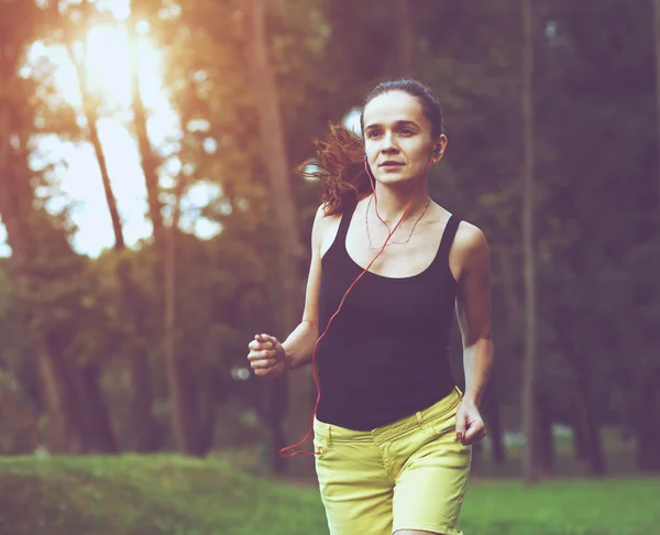 Mujer bastante deportiva corriendo en el parque en la luz del amanecer —  Fotos de Stock