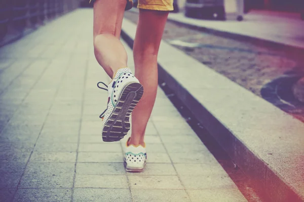 Una ragazza che fa jogging nel parco. Piedi in esecuzione su strada — Foto Stock