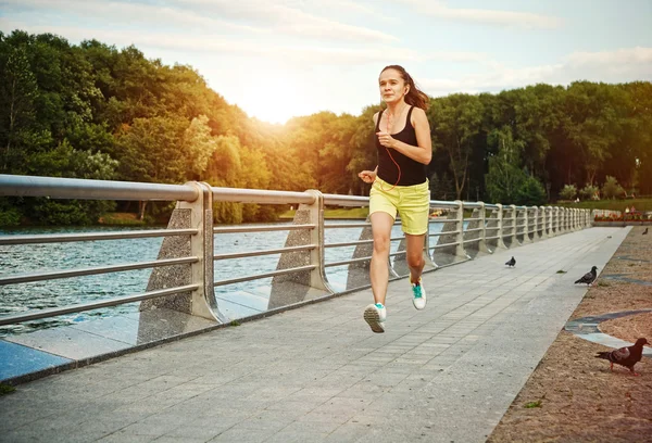 Ganska sportig kvinna joggar i parken i soluppgången ljus — Stockfoto