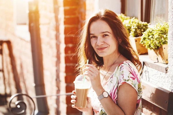 Pretty smiling girl with milk shake sitting on bench at street c — Stock Photo, Image