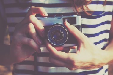 Retro kamera tutan ve fotoğraf çeken bir kız.