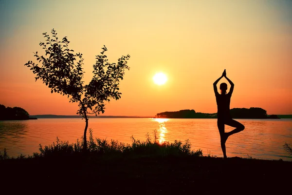 Mujer silueta practicando yoga posando en la playa al atardecer — Foto de Stock