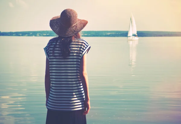 Kvinna som står ensam på havet kusten och titta på fartyget — Stockfoto