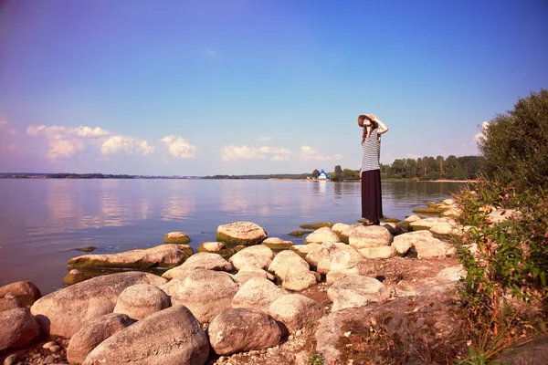 Жінка стоїть сама на морському узбережжі і дивиться на сонце — стокове фото