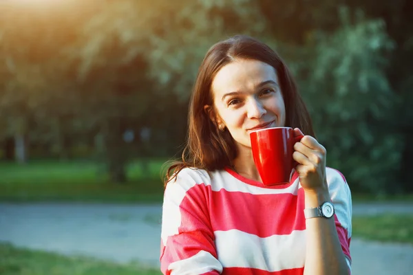 Lachende mooi meisje met koffie in de ochtend in park — Stockfoto