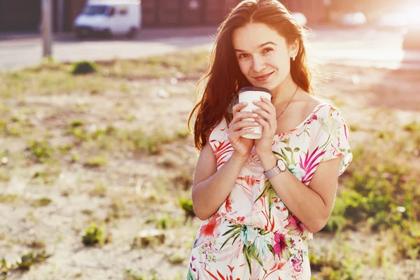 Lächelndes hübsches Mädchen, das mit Morgenkaffee auf der Straße spaziert — Stockfoto