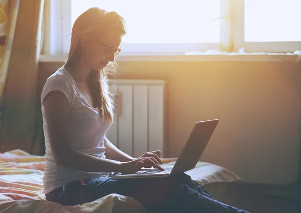 Wanita dengan laptop duduk di tempat tidur — Stok Foto