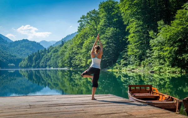 Yoga exercises at mountain forest lake.