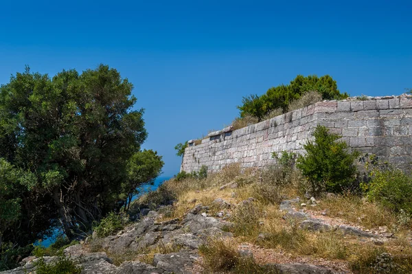 Muri di pietra di antica fortezza su per la collina — Foto Stock