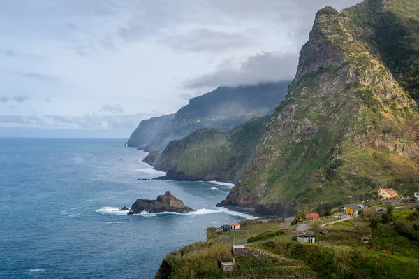 Isla de Madeira costa norte. Pequeño pueblo bajo montañas rocosas y vista al océano Atlántico — Foto de Stock