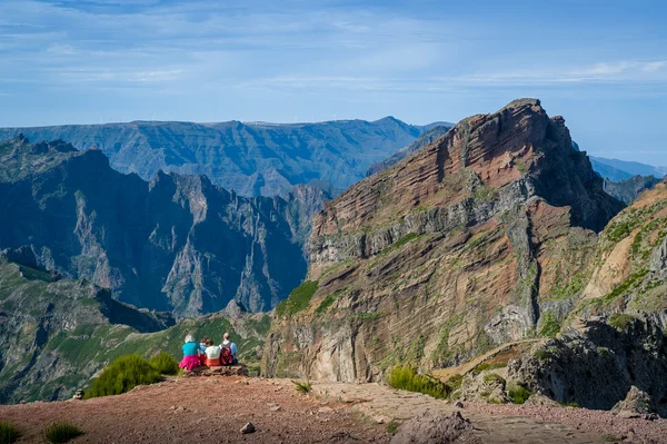 Gruppo di turisti è seduto sulla scogliera e guardando il paesaggio montano . — Foto Stock