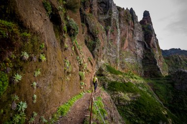 Woman hiker is going on the edge of steep mountain