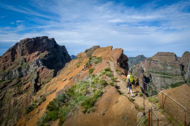 Woman hiker with green backpack is walking to Pico Ruivo hike