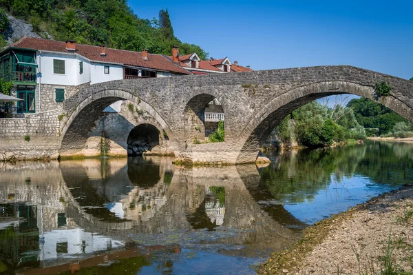 Rijeka Crnojevica viejo puente vista panorámica con reflejos sobre las tranquilas aguas del río . — Foto de Stock