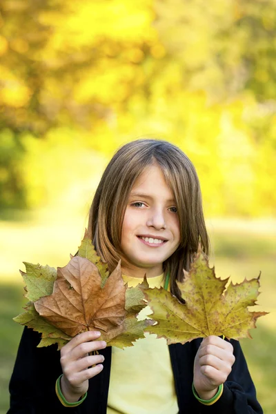 Bambino sorridente con foglie autunnali — Foto Stock