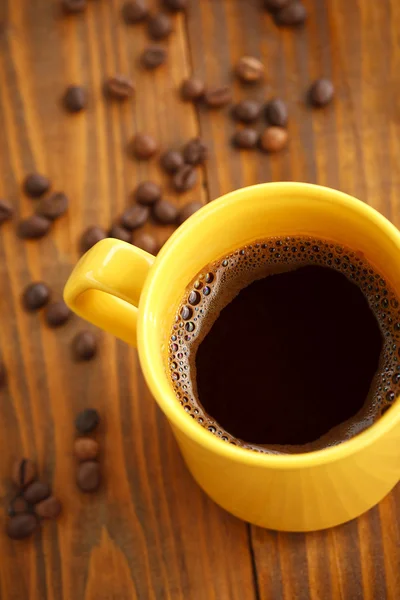 Xícara de café e grãos de café na velha mesa de madeira — Fotografia de Stock