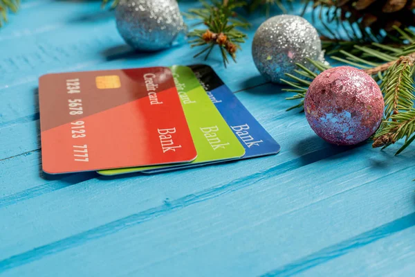 Fir, spruce branches, Christmas tree toys, credit cards on blue background with copy space