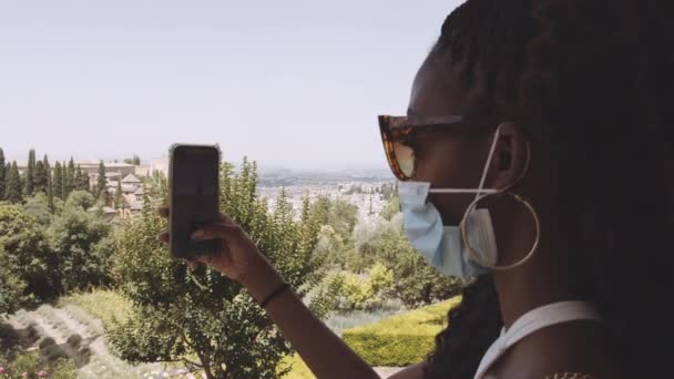 Ung kvinne i maske Suing Smartphone på Alhambra Palace – stockvideo