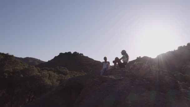 Drone Of Couple Sitting On Rocks In Sunlight — Stok Video