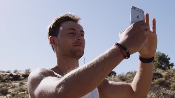 Молодий чоловік знімається зі смартфоном у сільській місцевості — стокове відео