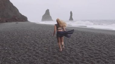 Kara Kum Sahili 'nin orada öğleden sonra çıplak ayakla koşan kadın dansçı.