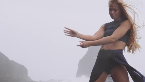 Mujer bailando alrededor de la playa negra mientras llueve mientras se inclina hacia atrás — Vídeos de Stock