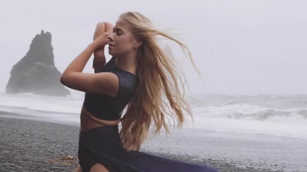 Woman Dancing Alone in a Black Beach with Strong Winds and Ocean Waters in Background — Stock Video