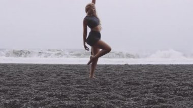 Black Sand Beach 'in orada, bale ayakkabılı bayan. Arka planda muhteşem dalgalar var.