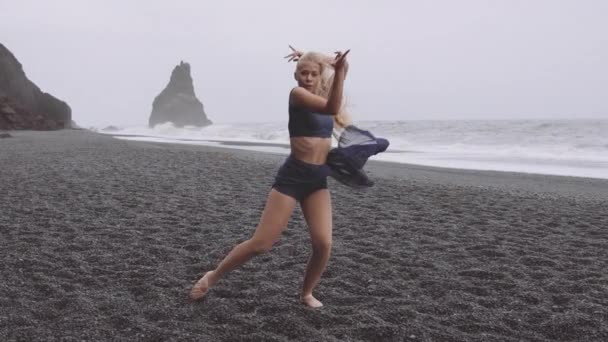 年轻的舞蹈家赤脚在黑沙滩上，情绪激昂 — 图库视频影像