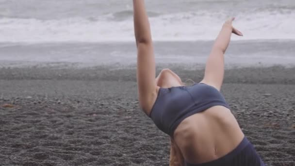 Flexibele vrouw dansen door het zwarte strand als ze leunt achteruit en dansen hartstochtelijk — Stockvideo