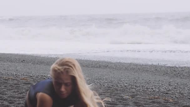 Szenische Wellen krachen gegen den schwarzen Strand, mit Tänzerin im Vordergrund — Stockvideo