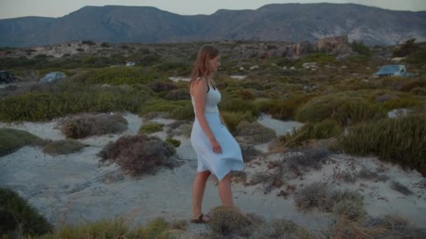 Mujer caminando aunque plantas de playa al atardecer — Vídeo de stock