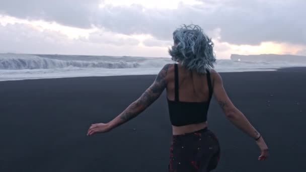 Ragazza dai capelli blu che corre sulla spiaggia di sabbia nera — Video Stock