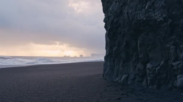 Playa de arena negra con olas de puesta de sol — Vídeo de stock
