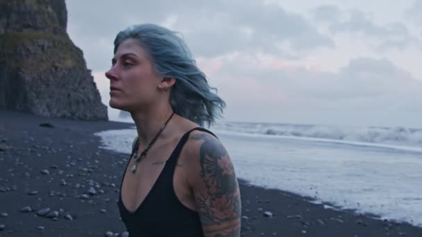風に吹かれた青い髪の女の子オンブラックビーチ — ストック動画