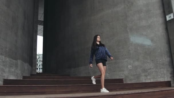 갈색 머리를 가진 십 대 소녀가 계단을 내려가는 거대 한 걸음을 내딛다 — 비디오