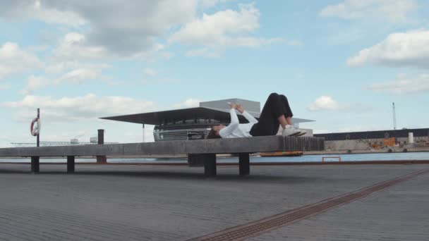 Підлітковий учень лежачи на лаві з телефоном на руках біля Портсайда — стокове відео