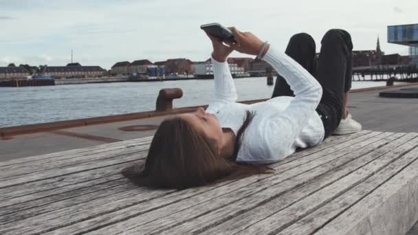 Junge Studentin legt sich auf eine Portbank in Kopenhagen, Dänemark — Stockvideo