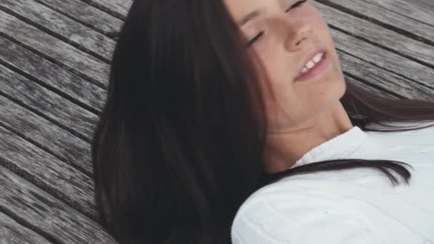 Fräknig vacker tonåring ligger ner på en utomhus bänk på en blåsig dag — Stockvideo