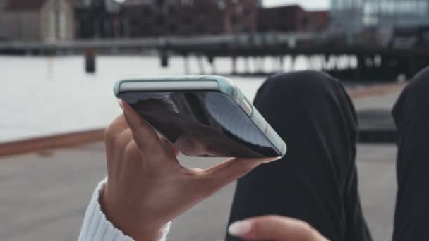 Detailní záběr ženských rukou na telefonu při ležení na lavičce u doků — Stock video